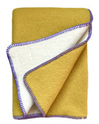 Reversible Norwegian merino wool plaid blanket in spicy mustard tone, soft brushed texture, jacquard weave, artisanal home textile.