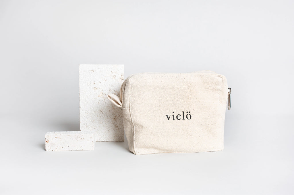 Premium organic cotton cosmetic pouch crafted in Austria by Vielö, minimalist silhouette, stitched logo detail, plastic-free natural fabric, timeless travel and everyday accessory. Dimensions: 15 × 5 × 13 cm.
