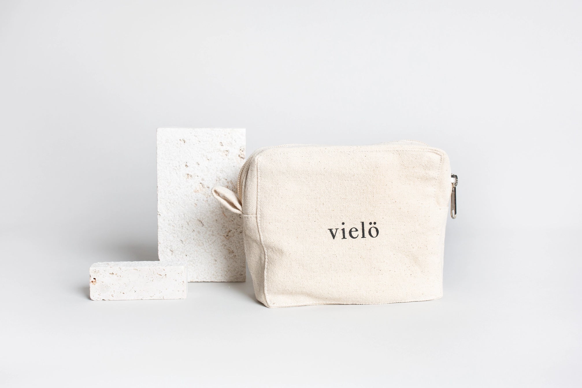 Premium organic cotton cosmetic pouch crafted in Austria by Vielö, minimalist silhouette, stitched logo detail, plastic-free natural fabric, timeless travel and everyday accessory. Dimensions: 15 × 5 × 13 cm.