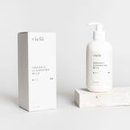 Organic cleansing milk by Vielö, creamy gentle texture, minimalist bottle design, chamomile, arnica and sage botanicals, daily makeup remover ritual.