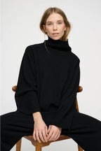 Black merino wool roll-neck (turtleneck) sweater, soft knit texture, timeless silhouette, minimalist wardrobe essential.