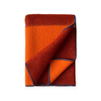 Reversible Norwegian merino wool plaid blanket in burgundy and orange tone, soft brushed texture, jacquard weave, artisanal home textile.
